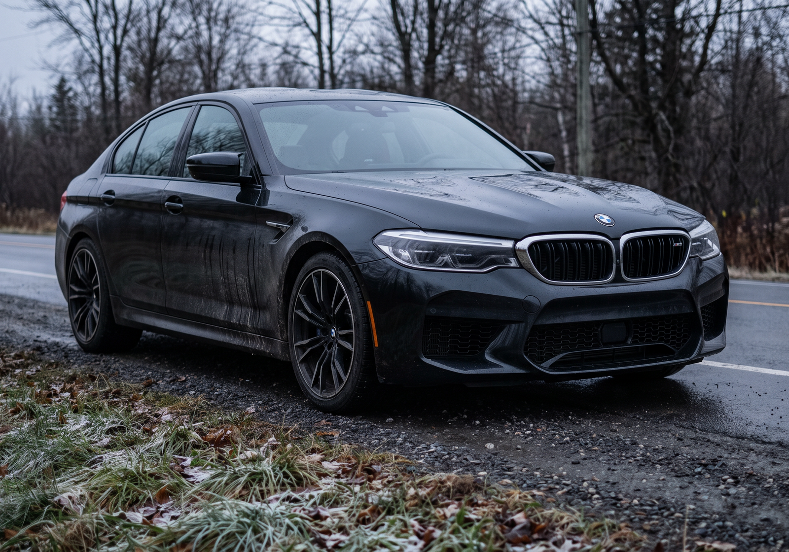 Realistic editorial photo of a black BMW M5 F90 on a wet roadside for AZ Motorsport BMW S63 M5 and X5M/X6M downpipe and exhaust guide