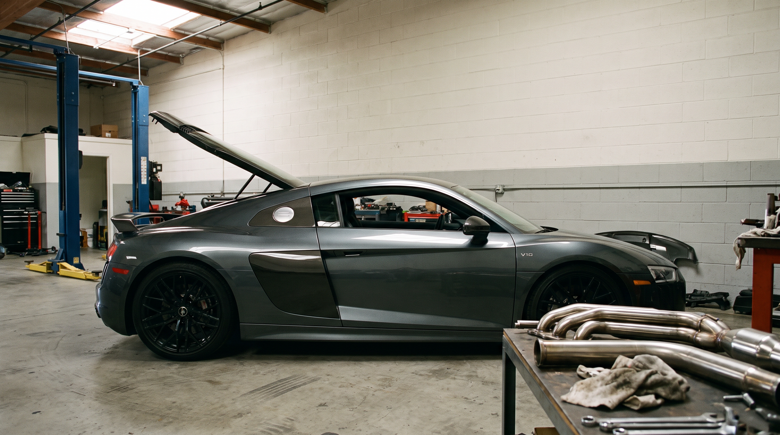 Audi R8 V10 coupe in a performance workshop with exhaust header tubing for a race headers buyer guide