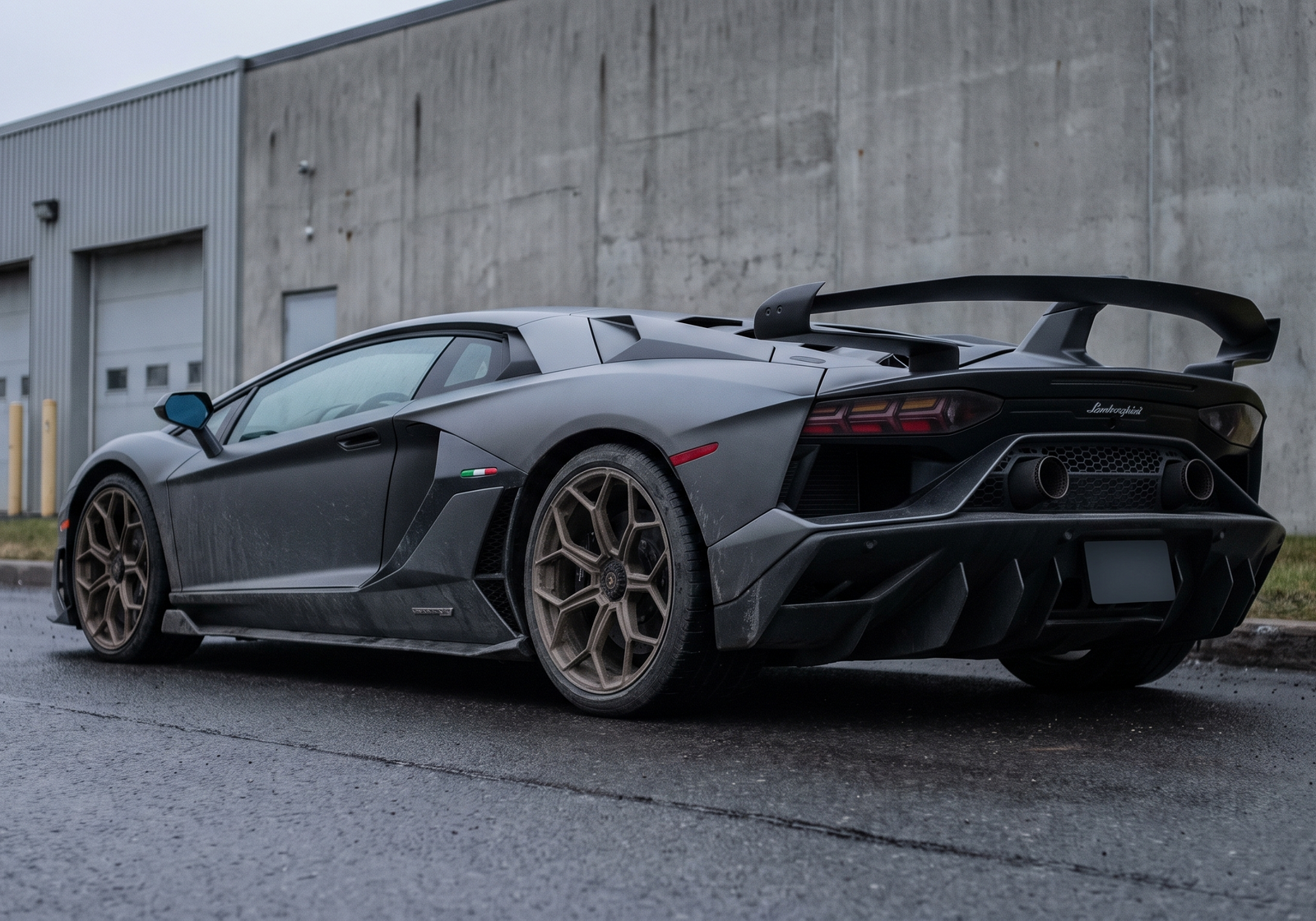 Illustration: grey Lamborghini Aventador SVJ rear three-quarter view on a wet industrial road with exhaust visible
