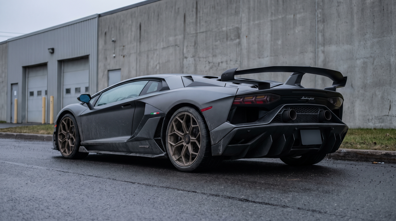 Illustration: grey Lamborghini Aventador SVJ rear three-quarter view on a wet industrial road with exhaust visible