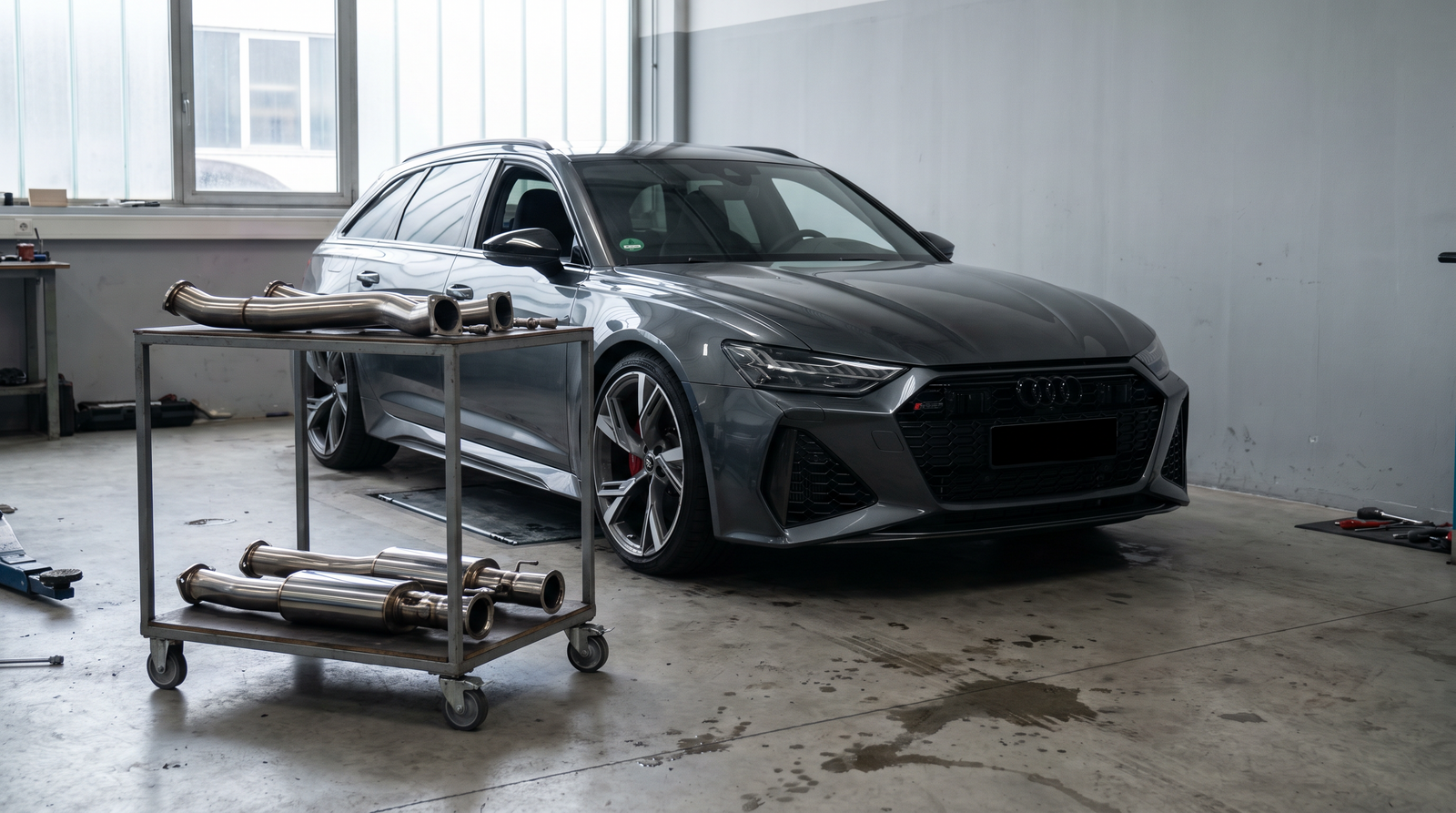 Grey Audi RS6 Avant C8 in a workshop with stainless downpipe sections for an RS6/RS7 downpipes guide