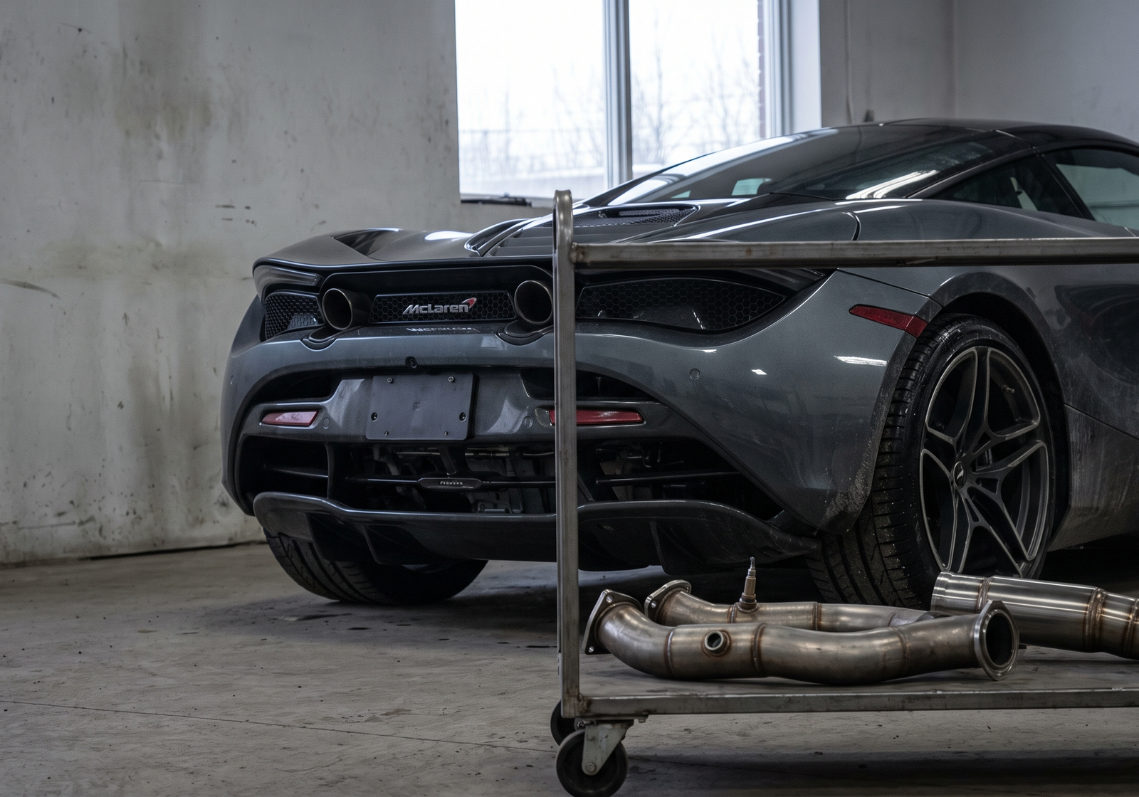 McLaren supercar in a performance workshop with downpipes and race exhaust parts for a fitment guide