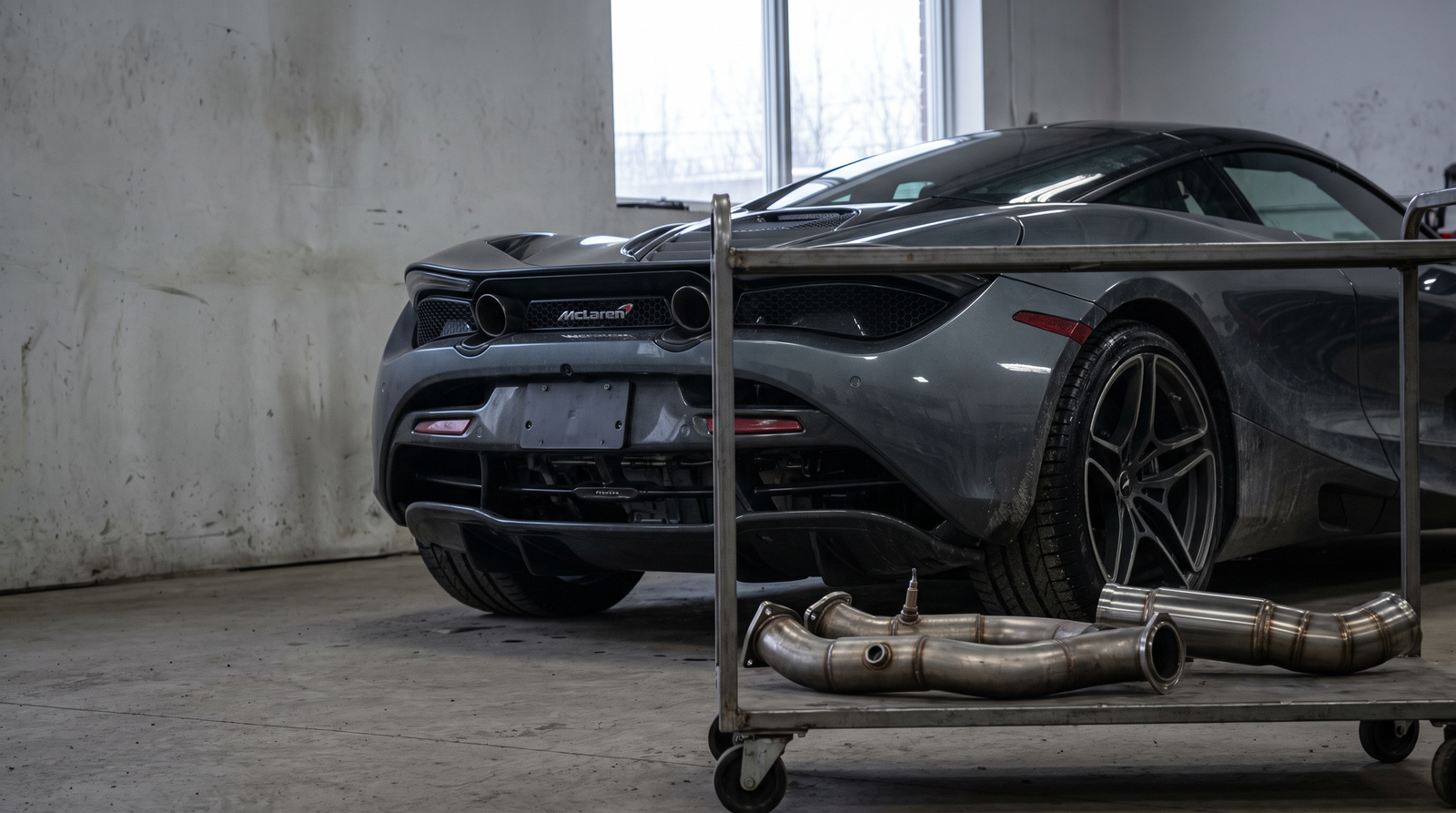 McLaren supercar in a performance workshop with downpipes and race exhaust parts for a fitment guide