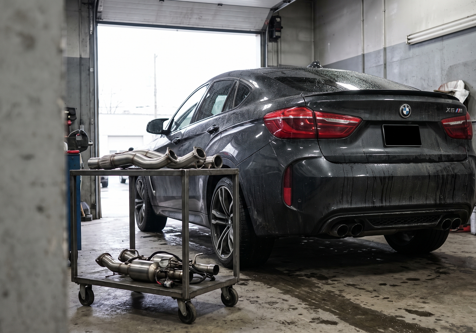 Illustration: dark BMW X5M/X6M-style performance SUV in a workshop with exhaust and downpipe components for an upgrade guide