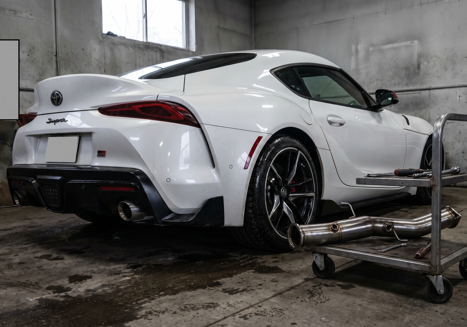 Illustration: white Toyota GR Supra A90-style coupe in a workshop with a downpipe section for a fitment and Stage 2 tuning guide