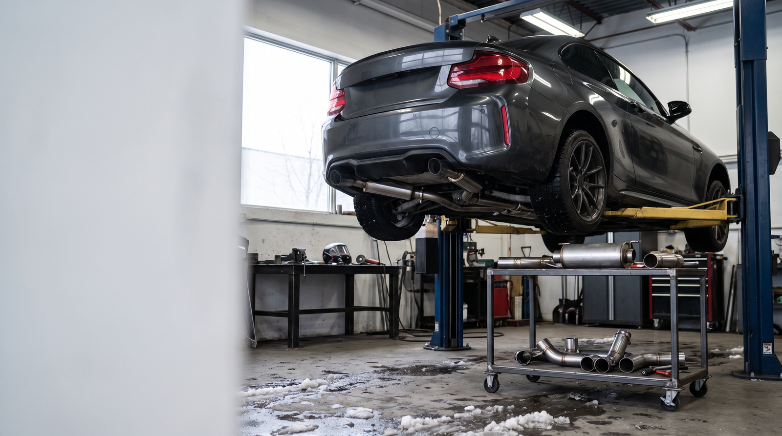 Performance exhaust workshop with a coupe on a lift and exhaust components for a Brossard custom fabrication checklist