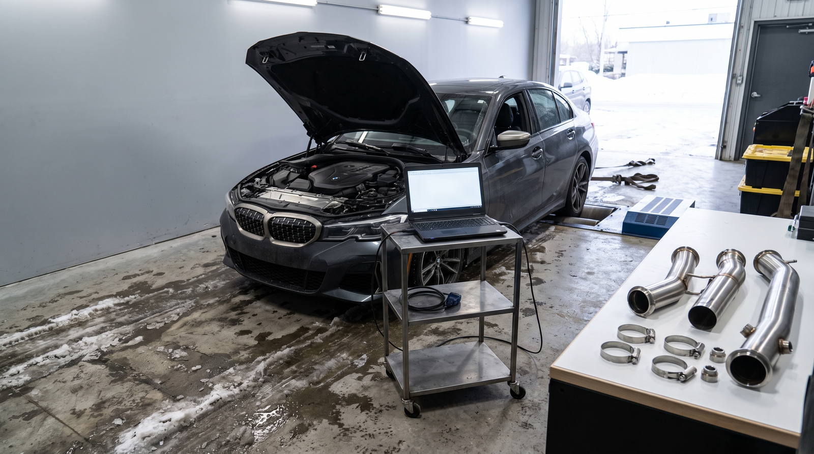 BMW M340i-inspired sport sedan in a Quebec tuning workshop with diagnostic laptop and downpipe parts for a tune, check engine light and fitment checklist