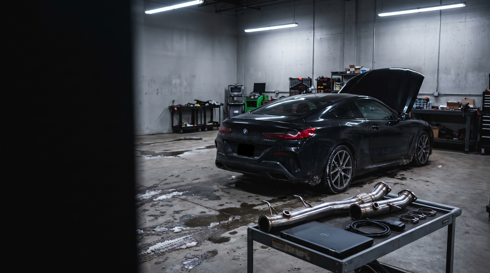 BMW M850i coupe in a Quebec performance workshop with downpipe parts and diagnostic equipment