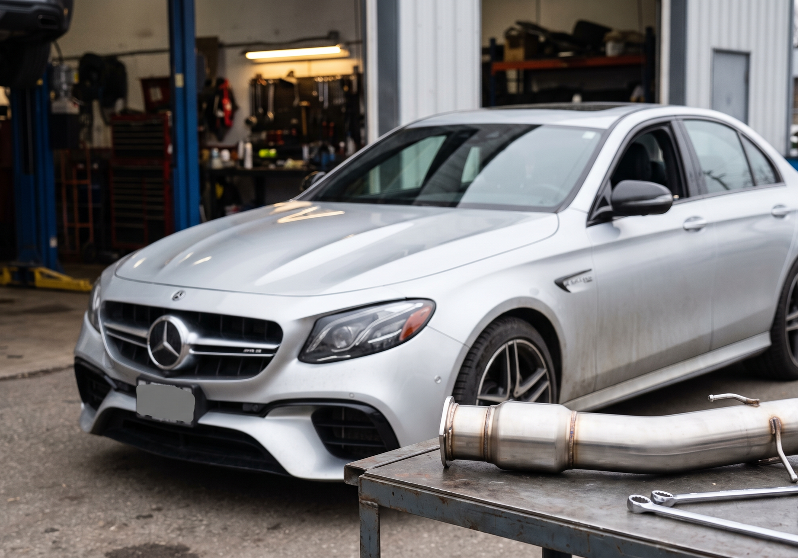 Mercedes-AMG E63 W213 in a workshop with a downpipe component for fitment and tune planning